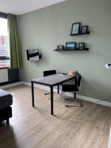 ヴァーヘニンゲンにあるShort Stay Wageningenのテーブル、椅子2脚、テレビが備わる客室です。