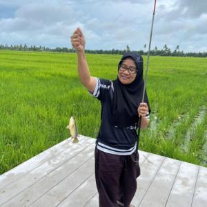 a woman is holding up a bow and arrow at Kurau Inn Farmstay in Kuala Kurau