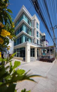 un edificio blanco alto con un restaurante frente a él en SLEEP TO FLY HOTEL & HOSTEL suvarnabhumi airport, en Bangkok