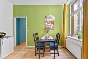 jadalnia z zielonymi ścianami i stołem z krzesłami w obiekcie Holiday 33 Apartments EFG Schönhauser Allee mit Balkon w Berlinie