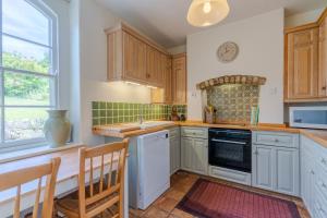 a kitchen with wooden cabinets and a table and chairs at Bluebell Cottage in Chippenham