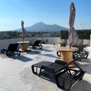 eine Terrasse mit Tischen, Stühlen und einem Sonnenschirm in der Unterkunft B&b Pompei Window in Pompei