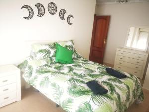 a bedroom with a bed with a green and white comforter at ORTEGA SUITE, dúplex en el centro de Luanco in Luanco