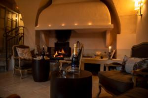 a living room with a fireplace and a table with a bottle of wine at Le Couvent D'Herepian in Hérépian