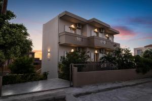 a large white building with a sunset in the background at Procris Villas Breathtaking Sea View in Kalathas