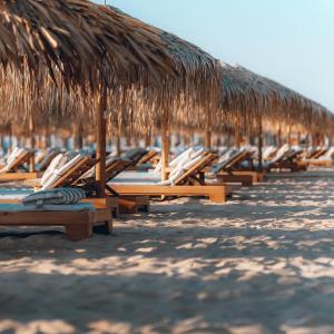 eine Reihe von Stühlen und Strohschirmen am Strand in der Unterkunft Long Beach Resort in Shkorpilovtsi