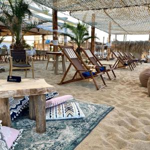 eine Gruppe von Stühlen und Tischen am Strand in der Unterkunft Long Beach Resort in Shkorpilovtsi
