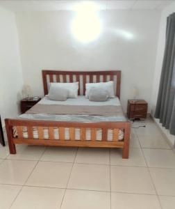 1 dormitorio con 1 cama de madera y 2 almohadas en Residence Delaure en Bingerville