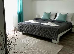 1 dormitorio con 1 cama grande con almohadas azules en Biloba Apartmanok, en Balatonlelle