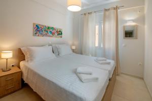 a bedroom with a white bed with towels on it at Casa Rossa e Verde by All About Paxos in Gaios