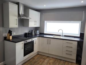 a kitchen with white cabinets and a sink and a window at The Admiral's Rest in Scarborough