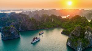 two boats in the water in a bay with mountains at Victory Star Cruise in Ha Long