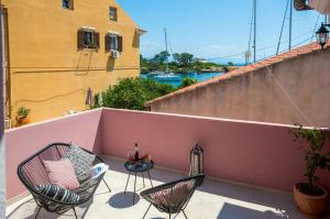 a patio with two chairs and a table on a balcony at Casa Rossa e Verde by All About Paxos in Gaios