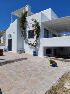 une maison blanche avec beaucoup de fleurs sur elle dans l'établissement Sophia & Chris Studios, à Santa Maria