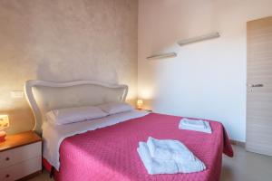 ein Schlafzimmer mit einem rosa Bett mit Handtüchern darauf in der Unterkunft Casa Vacanza Josephine in Barcellona-Pozzo di Gotto