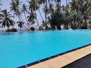 una grande piscina con palme sullo sfondo di Helios Beach Resort a Tangalle