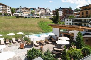 un hotel con un patio en la azotea con sillas y sombrillas en Hotel & Garni Das Köhle - inklusive der SUPER SOMMER CARD IM SOMMER 2024 en Serfaus