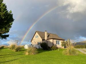 een regenboog over een huis met een groene tuin bij Toradale B&B in Skeabost