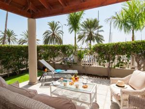 a patio with a table and chairs and palm trees at Bungalow Marina Deluxe in Pasito Blanco