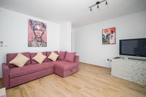 a living room with a purple couch and a flat screen tv at Piña Tourist Apartments in Vodice