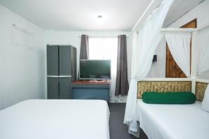a bedroom with two beds and a television in it at 8 Colors Beach House Resort in Boracay