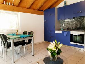 eine Küche mit blauen Schränken und einem Tisch mit Stühlen in der Unterkunft Haus Artemis in Saas-Grund