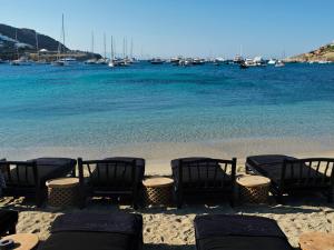 um grupo de cadeiras numa praia com a água em Myconian O, a Member of Design Hotels em Ornos
