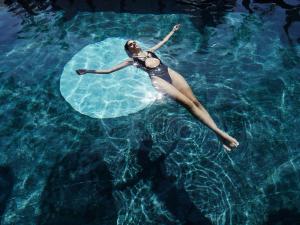 uma mulher está nadando em uma piscina de água em Myconian O, a Member of Design Hotels em Ornos