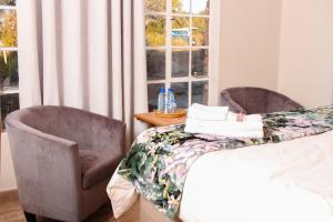1 dormitorio con 2 sillas, 1 cama y 1 ventana en Harnham Mountain Lodge, en Louis Trichardt