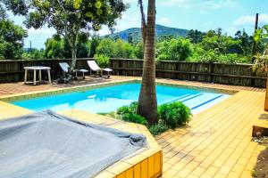 a swimming pool with a table and chairs and a tree at Harnham Mountain Lodge in Louis Trichardt