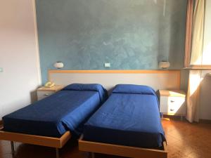 una camera con due letti con lenzuola blu di Aquila Nera Di Tony a Ivrea