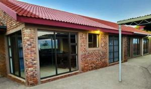 a brick building with glass doors and a red roof at Zea 85 BnB in Vereeniging