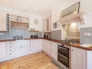 una grande cucina con armadi bianchi e pavimenti in legno di The Old Newsagents ad Alnwick