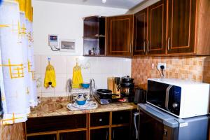 een keuken met houten kasten en een magnetron bij Royal Haven A1 Apartment in Mombasa - Bamburi, 50" HDTV, WiFi, 6 mins to Beach in Mombasa