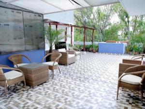 a patio with wicker chairs and tables on a tile floor at Maplewood Guest House, Neeti Bagh, New Delhiit is a Boutiqu Guest House - Room 3 in New Delhi