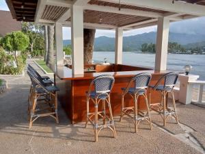 eine Bar mit Stühlen und einer Theke mit Blick auf das Wasser in der Unterkunft Casalay Boutique Villas & Dive in Puerto Galera