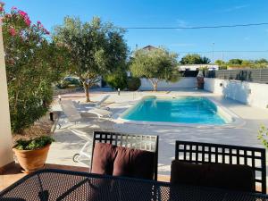 a swimming pool on a patio with two chairs at Apartmani Svemir in Drage