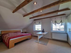 a bedroom with a bed and a table and two windows at Ferienhaus Im Hasengrund in Dornumersiel