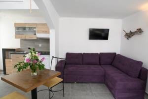 a living room with a purple couch and a table at Lakki Village in Aegiali