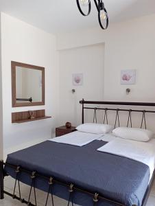 2 Betten in einem weißen Zimmer mit einem Spiegel und einem 6 x 6 cm großen Bett in der Unterkunft Sofirene I in Batsi