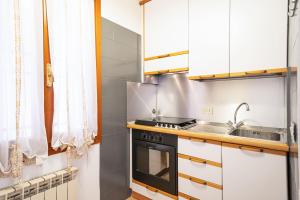 una cucina con armadi bianchi e piano cottura di ORMESINI home a Venezia