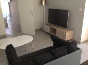 ein Wohnzimmer mit einer Couch, einem Tisch und einem Fernseher in der Unterkunft Gite de Manon in Bozouls