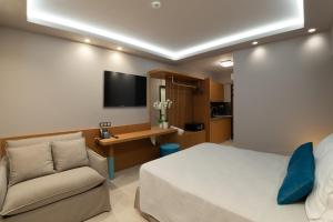 a bedroom with a bed and a couch and a tv at Lithos Suites - Nikiti Halkidiki in Nikiti