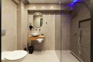 a bathroom with a toilet and a sink and a shower at Lithos Suites - Nikiti Halkidiki in Nikiti