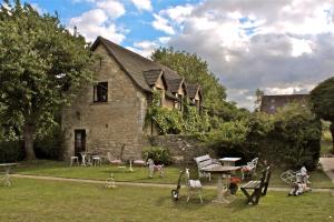 una casa antigua con un patio con sillas y mesas en Fosse Farmhouse Holiday Cottages en Chippenham