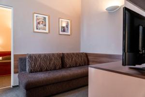 a living room with a couch and a television at Hotel Grand in Uherské Hradiště