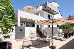 een huis met een patio met een parasol en stoelen bij Home and Business - Wohnen auf Zeit in Burgau