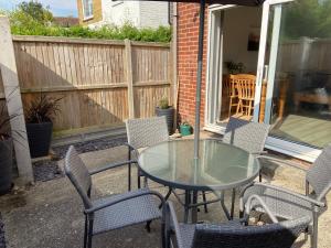 un patio con mesa de cristal y sillas en The Seagull, with driveway and patio garden, en Whitstable