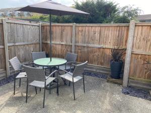 una mesa y sillas con una sombrilla en el patio en The Seagull, with driveway and patio garden, en Whitstable