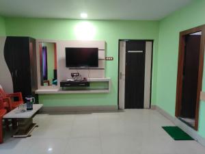 a living room with a tv on a green wall at Ditto Room Hotel Kartik, Deoghar in Deoghar